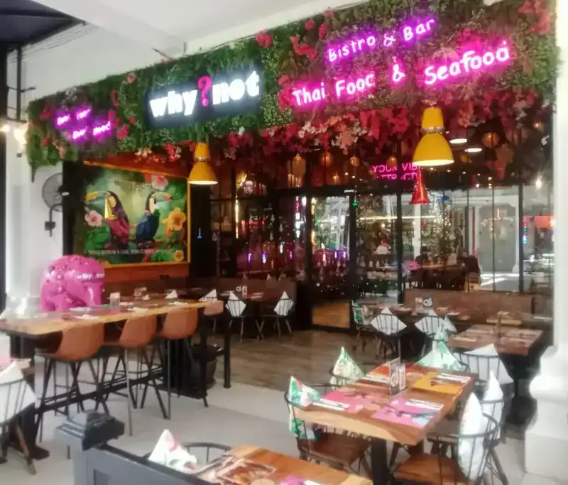 The shopfront in Jungceylon with its why?not sign, flower wall and tables out front / หน้าร้านในจังซีลอน ป้ายชื่อร้าน ผนังดอกไม้ และโต๊ะหน้าร้าน