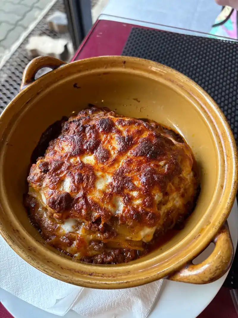 Lasagne with a browned cheese top in a yellow clay dish with handles