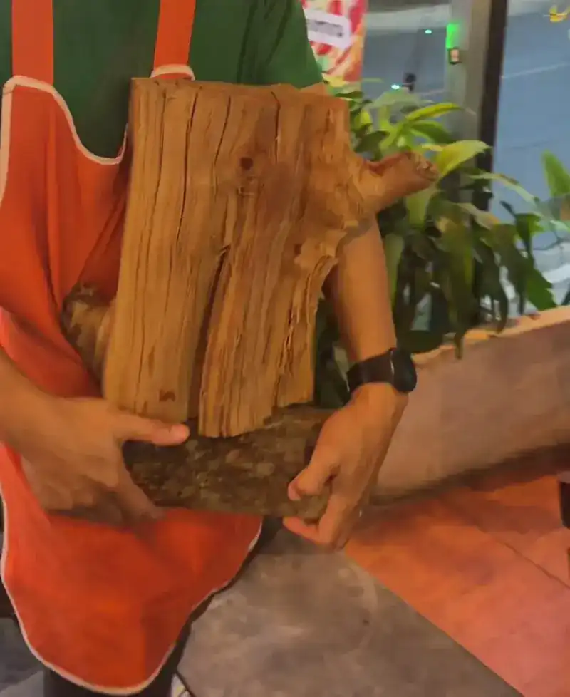 Hands carrying a split log of firewood