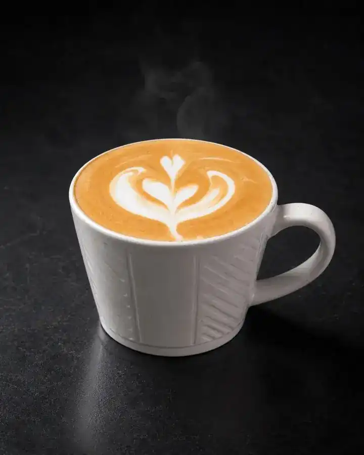Hot latte with latte art in a white ribbed mug