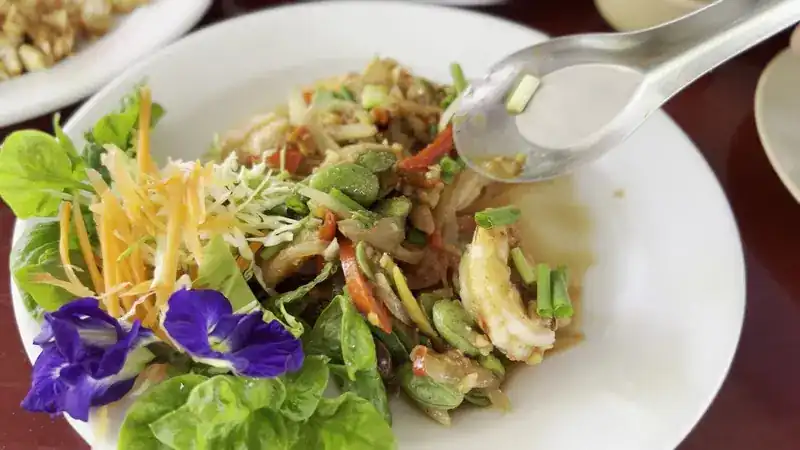 A spicy salad with stink beans, fresh herbs and butterfly pea flowers