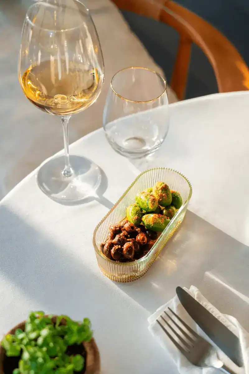 Green and black olives in a ribbed glass dish in the sun