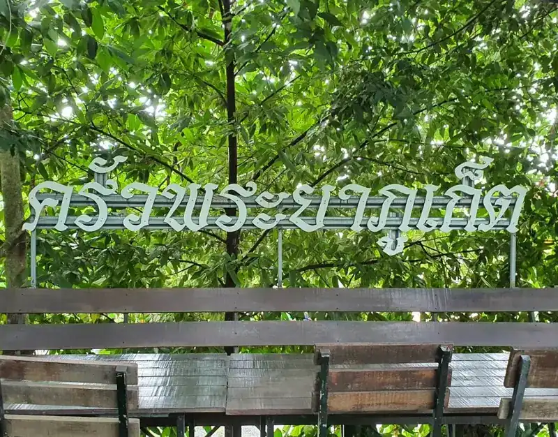 The restaurant's name sign up in the trees above wooden garden tables