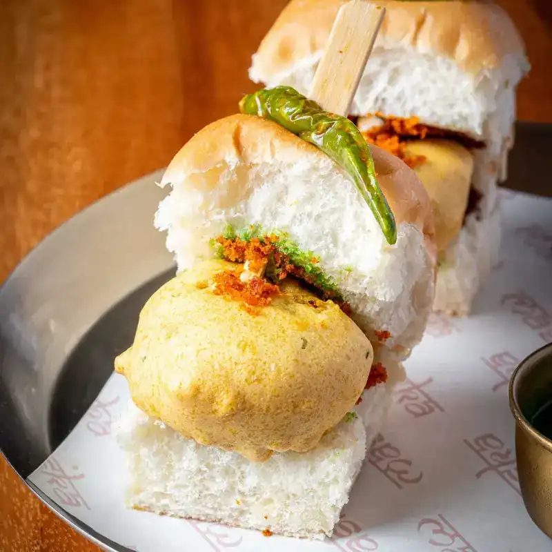 A potato fritter in a soft bun, topped with a fried green chilli