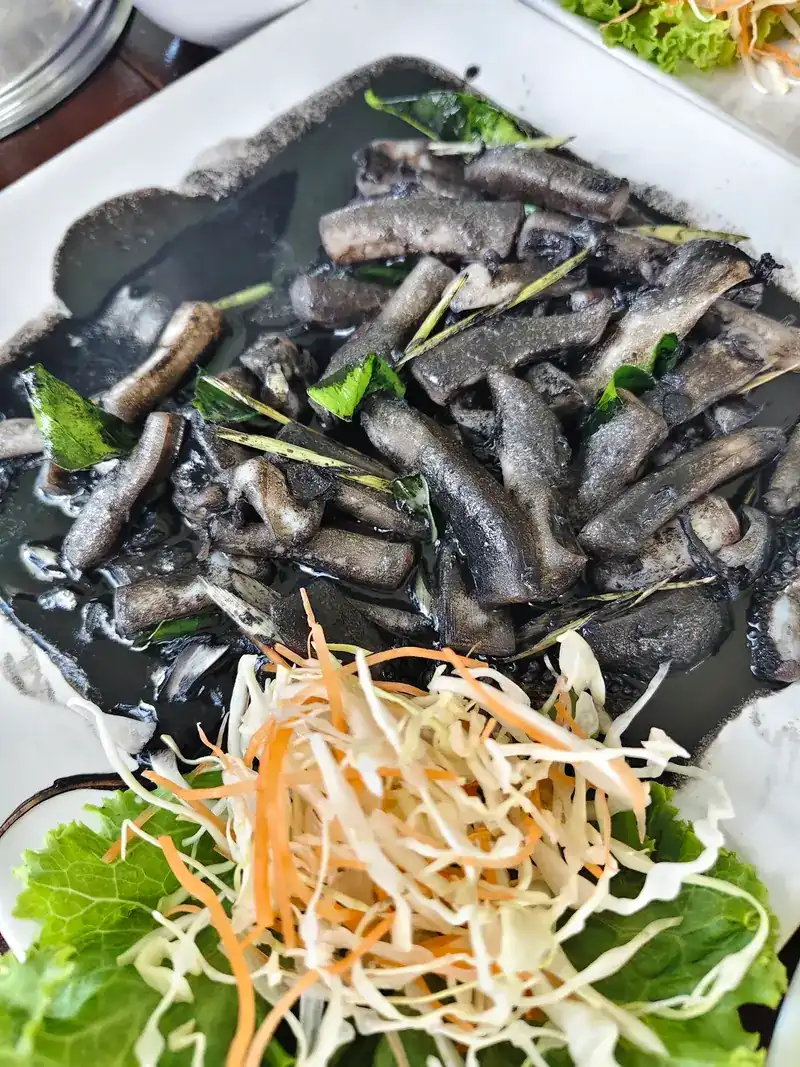 Squid stir-fried in its black ink, served with shredded cabbage and carrot