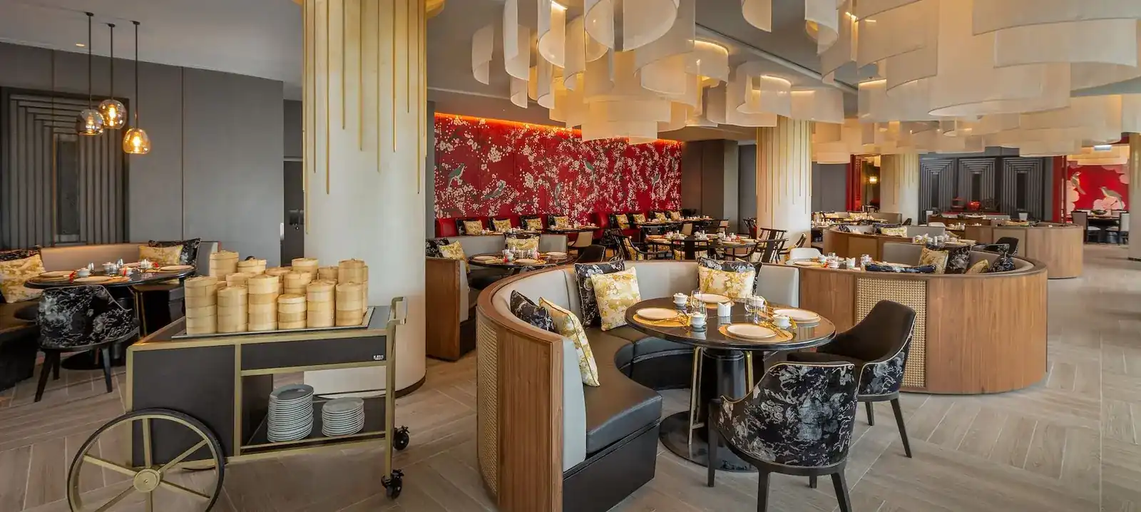 The dining room at Yue, a dim sum trolley stacked with bamboo steamers beside curved booths