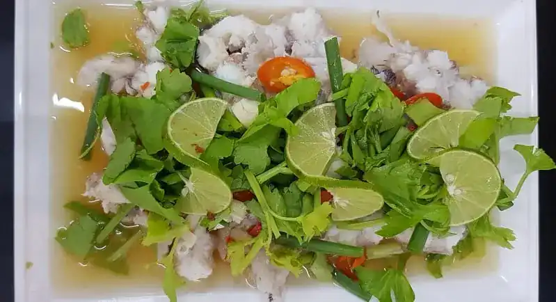 Steamed shark with lemon sauce, lime slices and fresh herbs