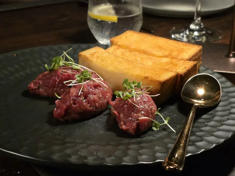 Beef tartare with fingers of toast on a dark plate / ทาร์ทาร์เนื้อกับขนมปังปิ้งบนจานสีเข้ม