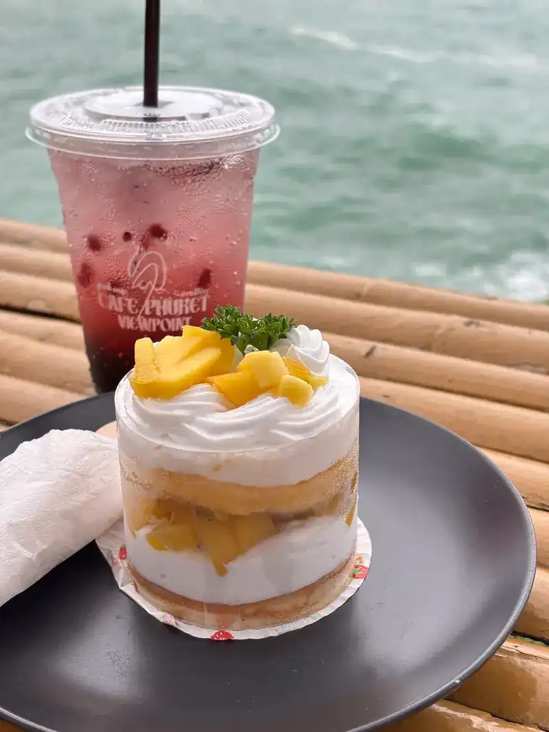 Mango cake and a red soda on the bamboo rail, the sea behind / เค้กมะม่วงกับโซดาสีแดงบนราวไม้ไผ่ มีทะเลอยู่ด้านหลัง