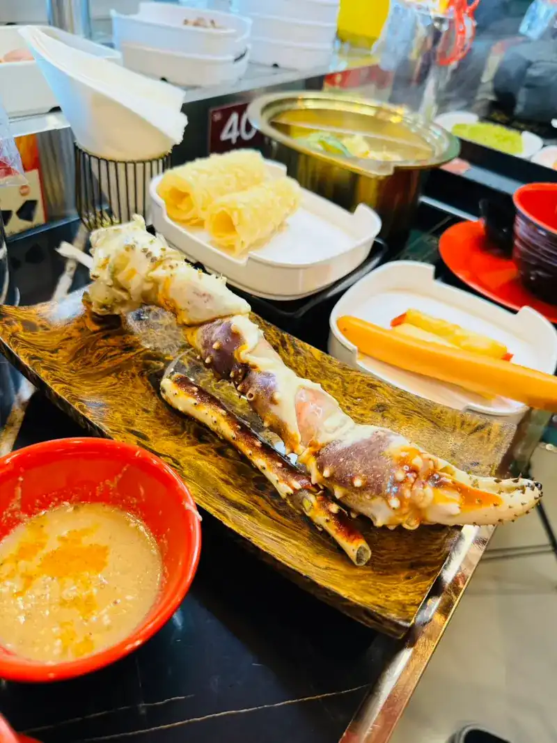 Grilled crab legs on a plate with a bowl of dipping sauce
