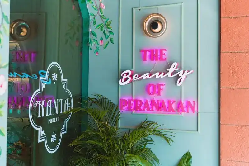 The pale turquoise shophouse door with a pink neon sign reading The Beauty of Peranakan