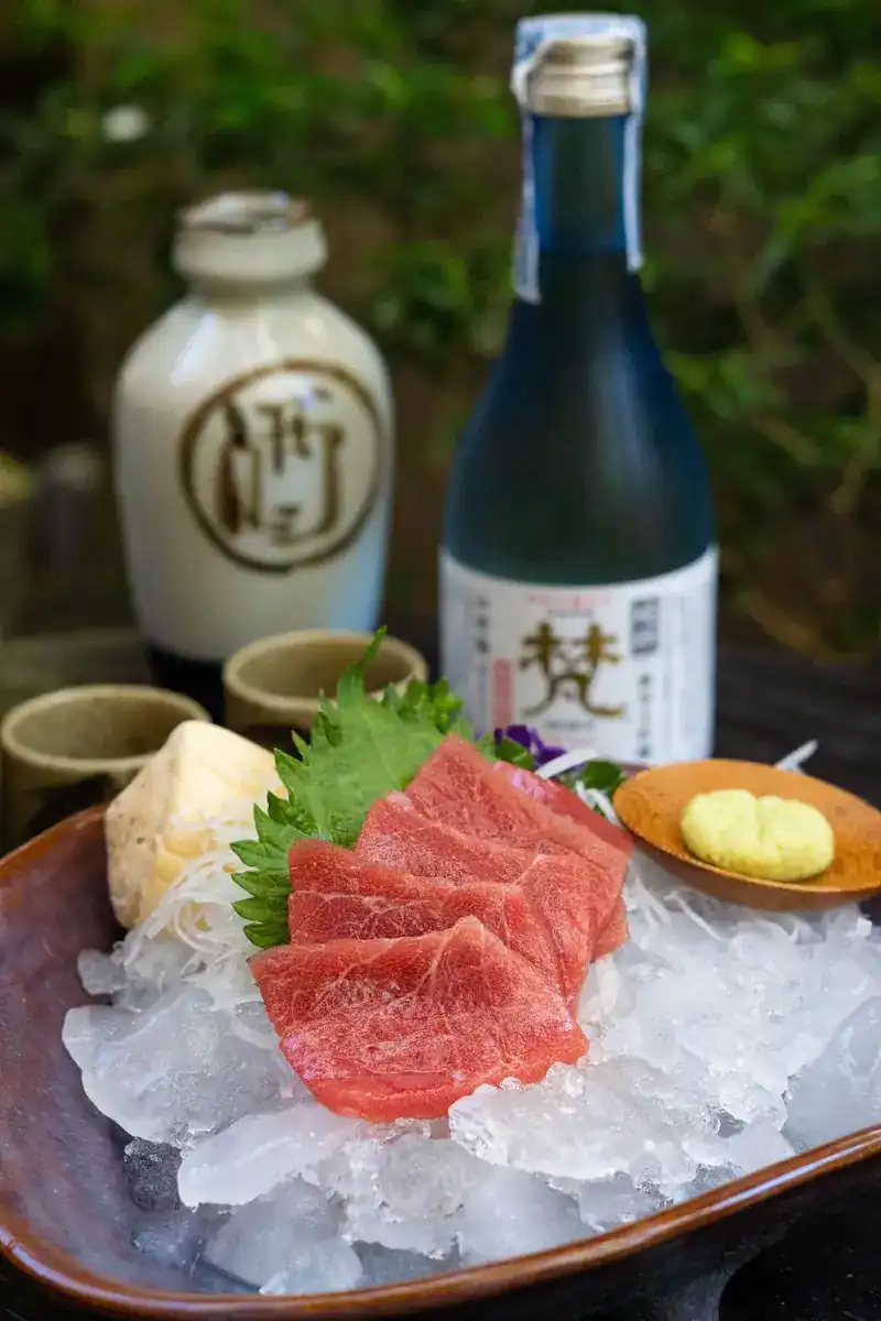 Slices of blue fin tuna on crushed ice with a shiso leaf