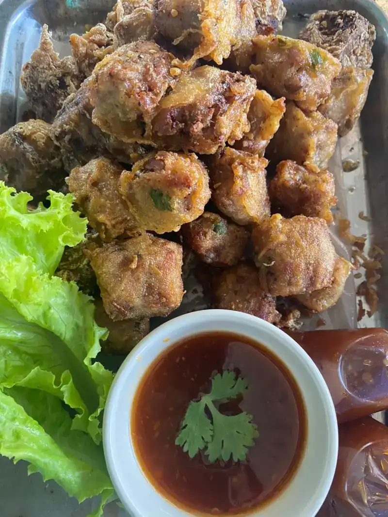 Golden fried pieces on a tray, with lettuce and a bowl of dark dipping sauce