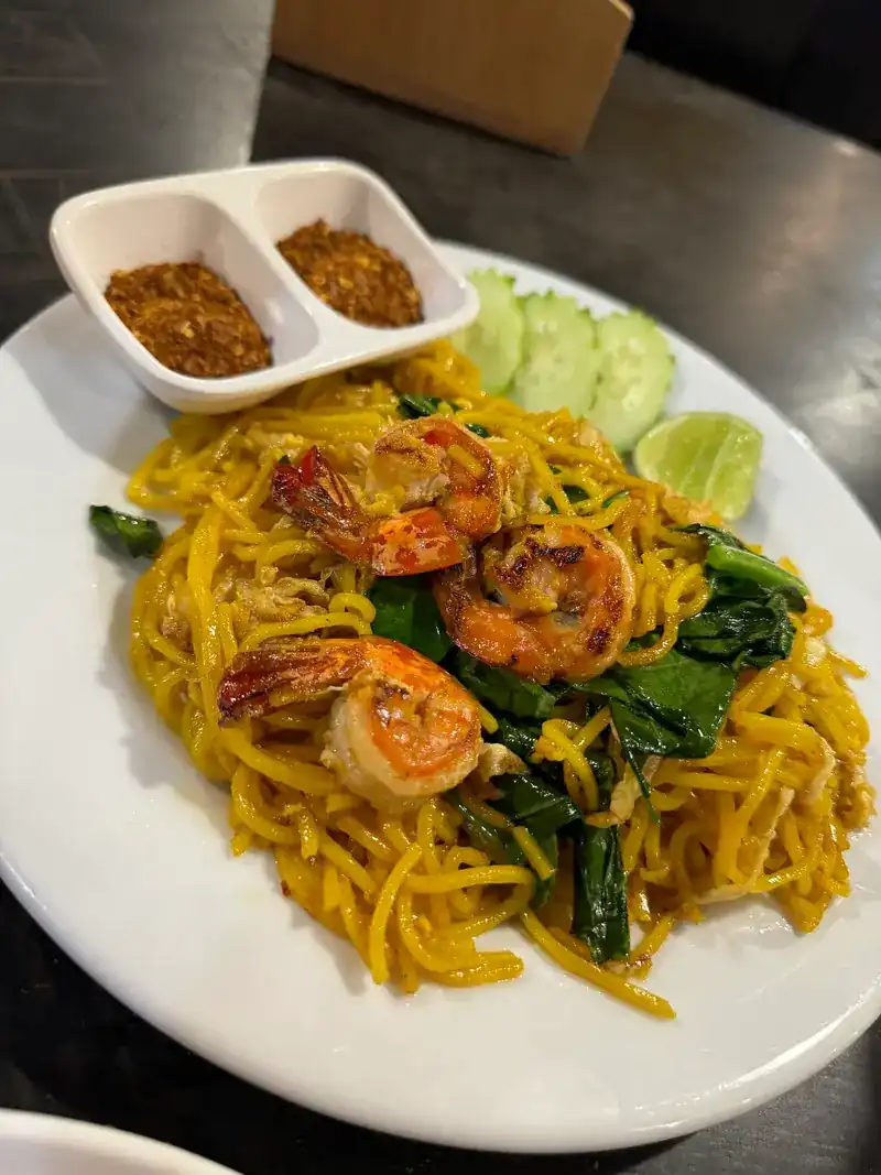 Yellow noodles fried with prawns and greens, with lime, cucumber and two small dishes of chilli