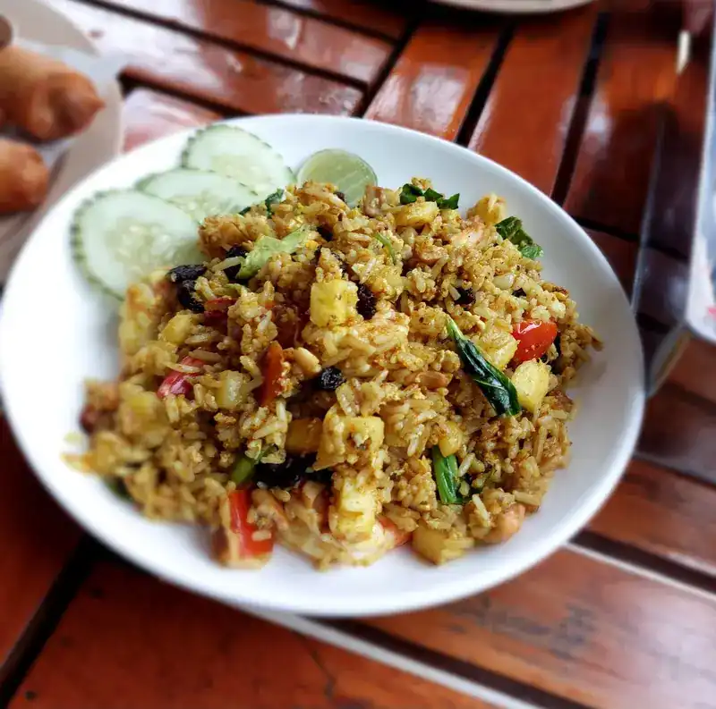Golden fried rice with pineapple, with cucumber and lime on the side