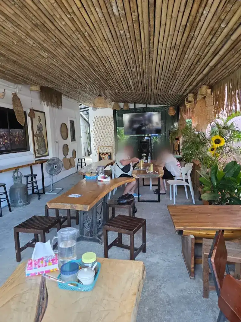 The dining area under the bamboo ceiling, with slab tables, stools and plants