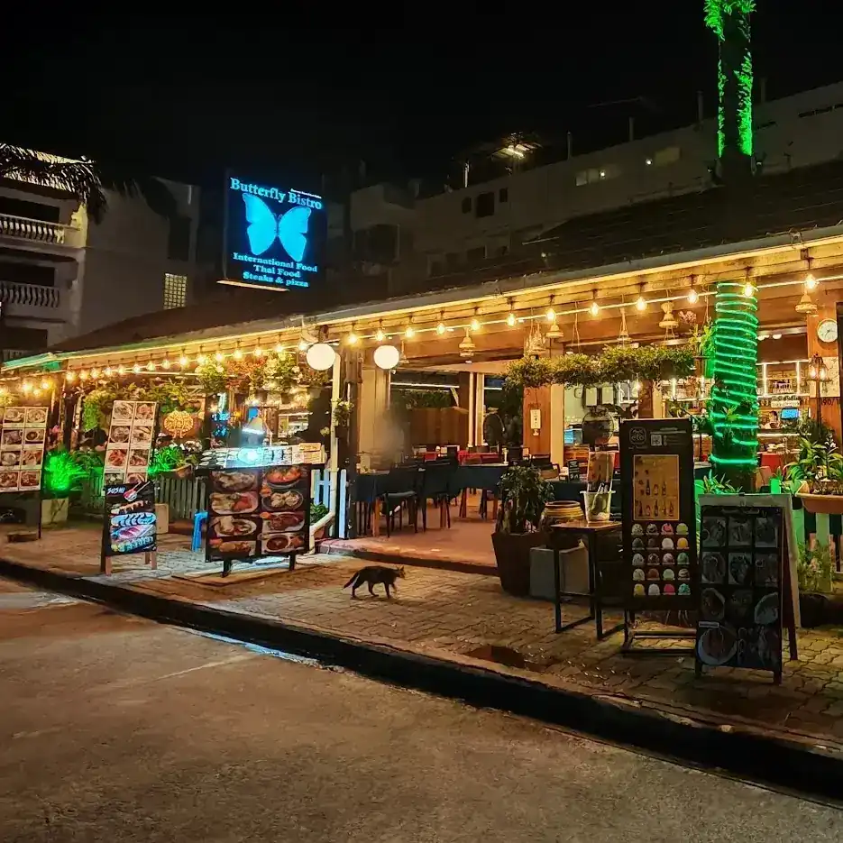 Butterfly Bistro at night: the lit blue butterfly sign above the terrace on Soi Withet