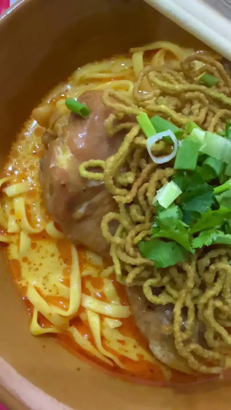 Khao soi with a chicken drumstick and spring onion