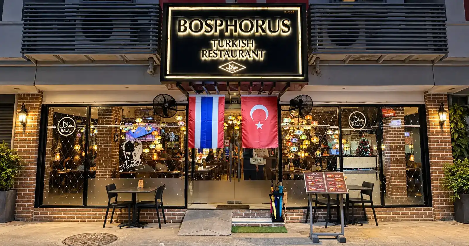 The restaurant front at night: the lit Bosphorus sign above the Thai and Turkish flags