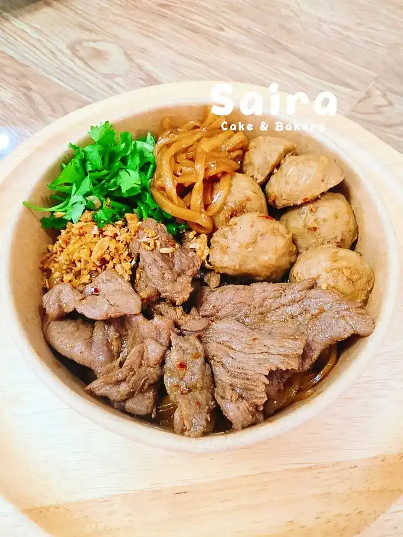 A bowl of sliced meat and meatballs with coriander and fried garlic