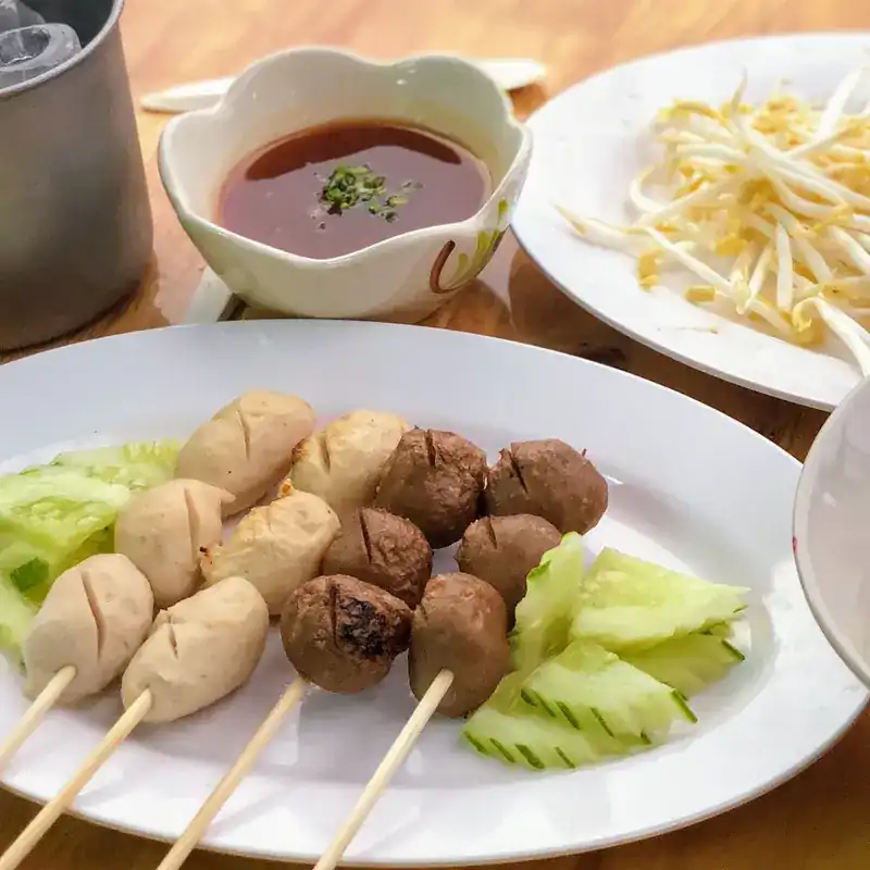 Grilled meatball skewers with dipping sauce, cucumber and bean sprouts