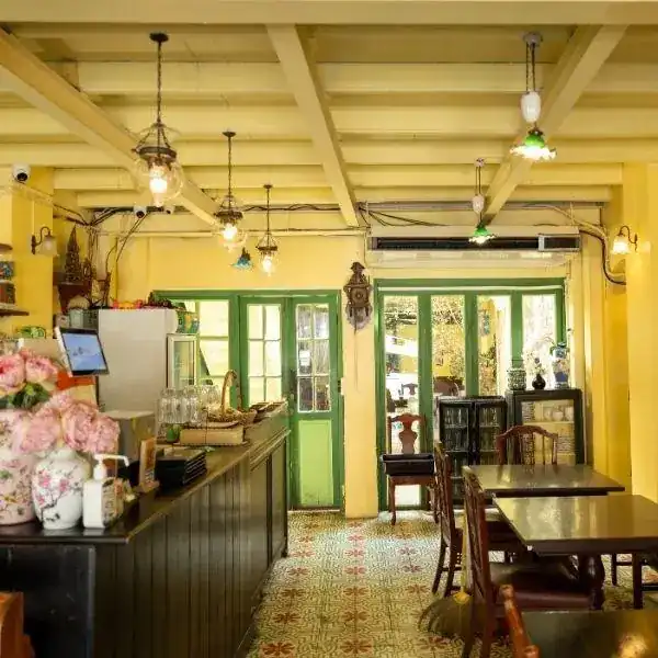 Inside One Chun: yellow walls, green doors, patterned floor tiles, wooden tables and glass lamps hanging from the beams