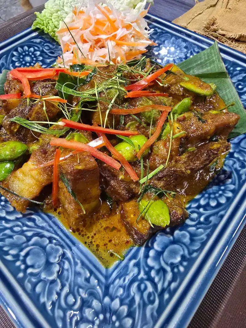 Pork stir-fried with sator beans and red chilli on a blue patterned plate