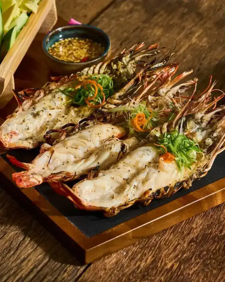 Grilled river prawns split open on a slate board