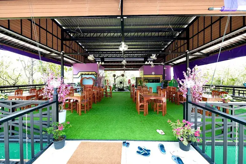 Inside the pavilion: green turf floor, wooden tables and chairs, purple walls and pink blossom