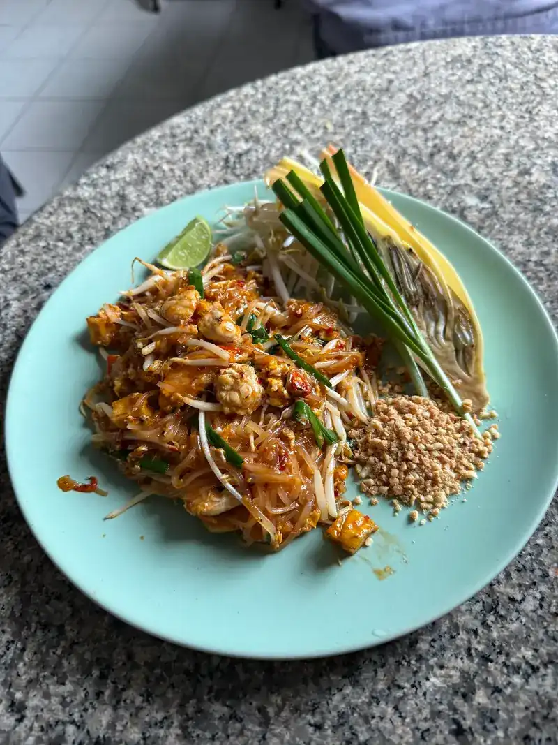 Pad Thai on a mint-green plate with chives, bean sprouts and crushed peanuts