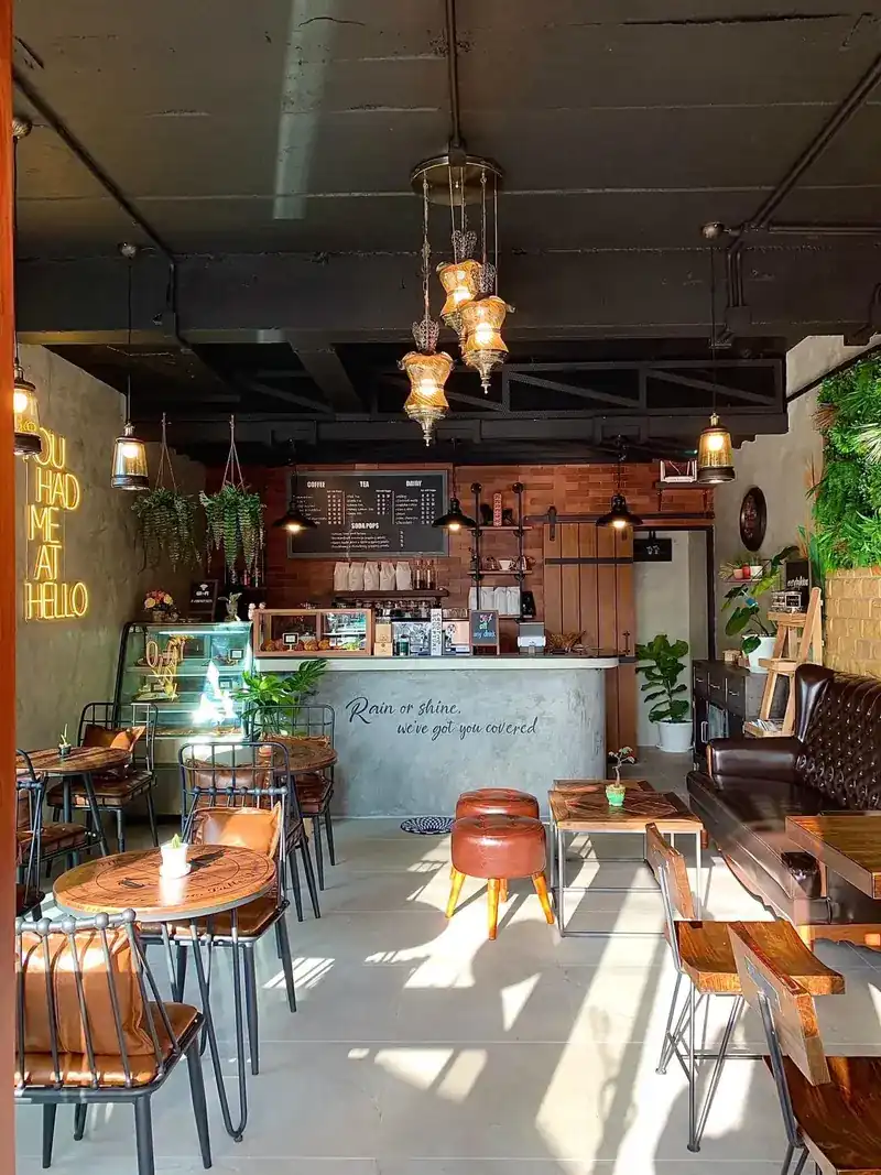 The room in the sun: hanging lanterns, leather stools, a leather sofa, ferns and the counter