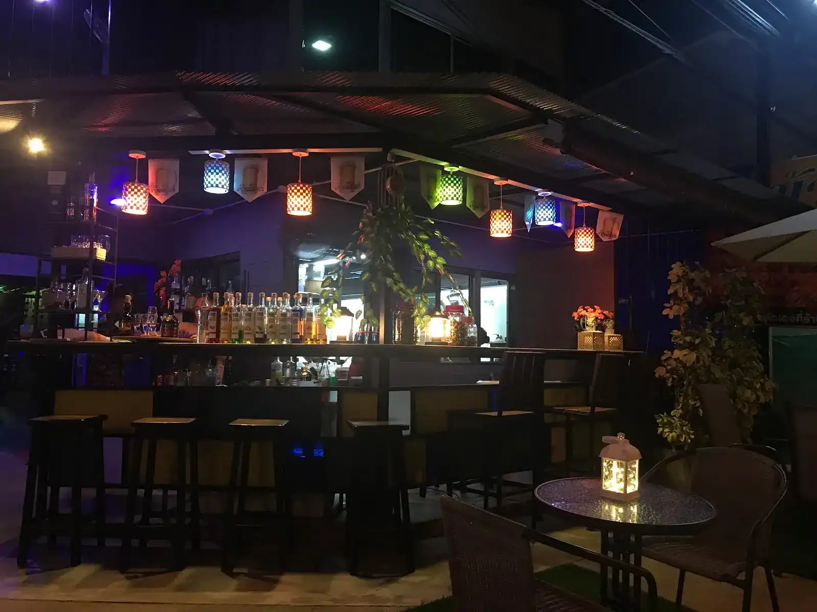 The bar at night under coloured lanterns, with a lantern-lit table in front