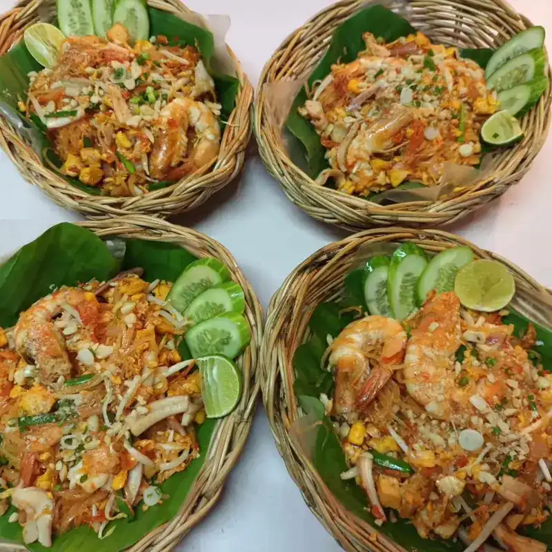 Four baskets of pad thai with prawns, cucumber and lime