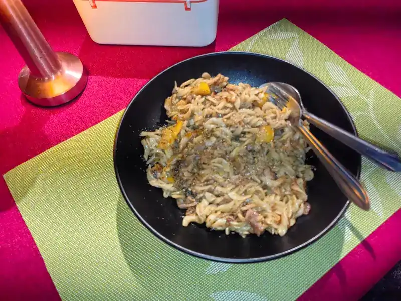 A bowl of pasta on a green placemat and a pink tablecloth