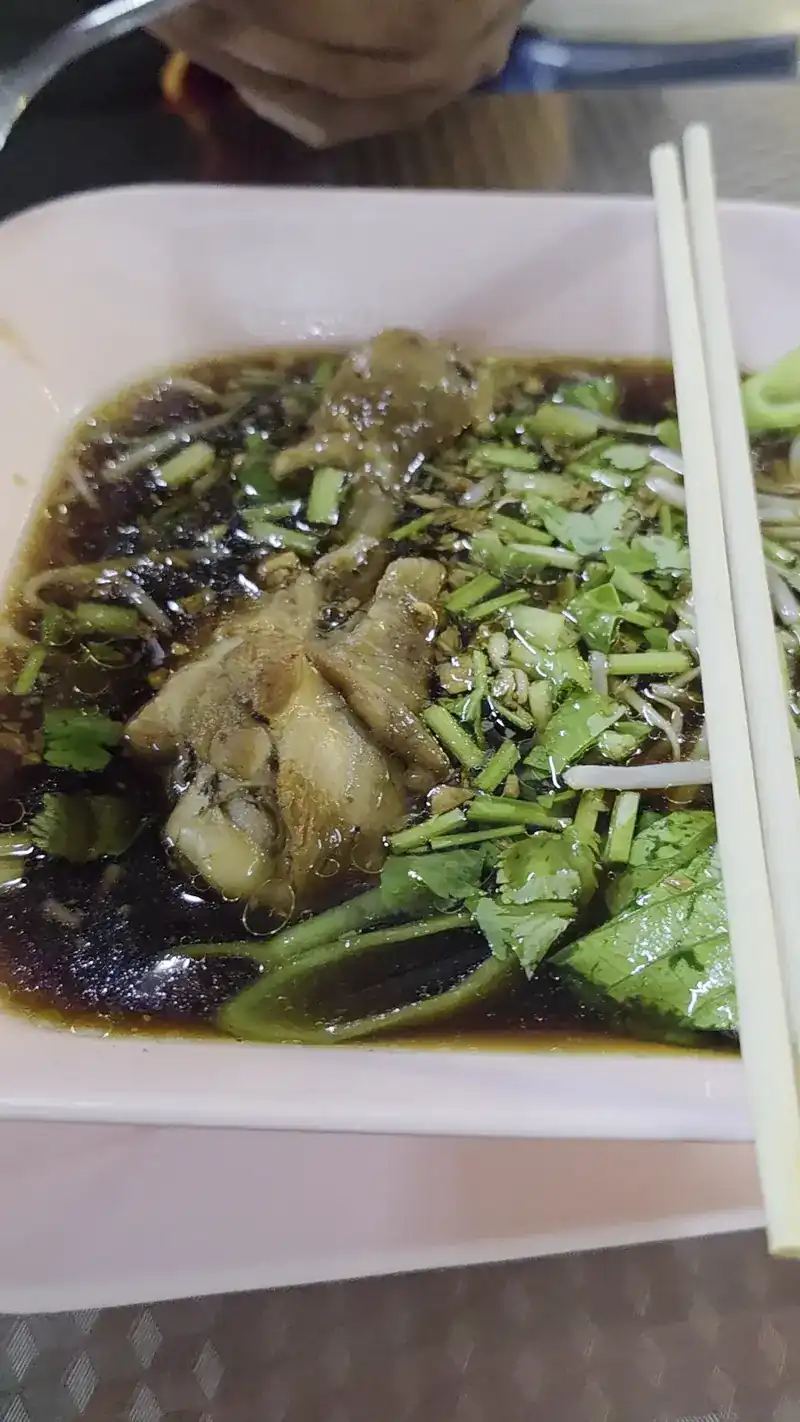 Noodle soup in a dark broth with greens, chopsticks resting on the bowl