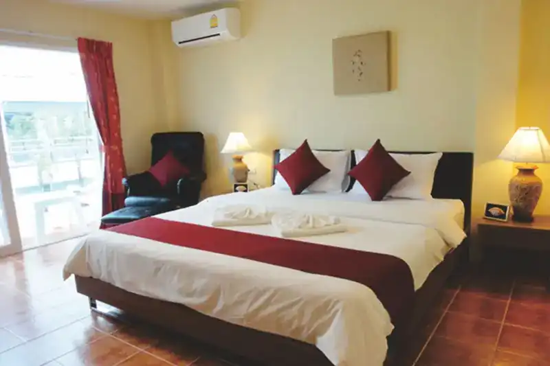 A double room with a king-size bed, red cushions and a door to the balcony