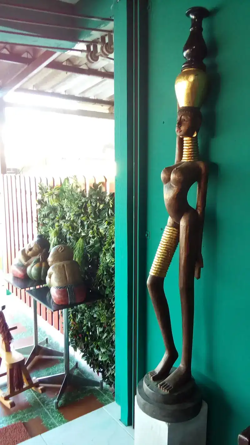 A tall carved wooden figure against the green wall