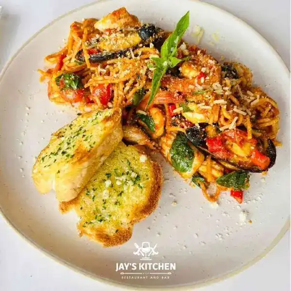 Seafood spaghetti in tomato sauce with garlic bread on a white plate