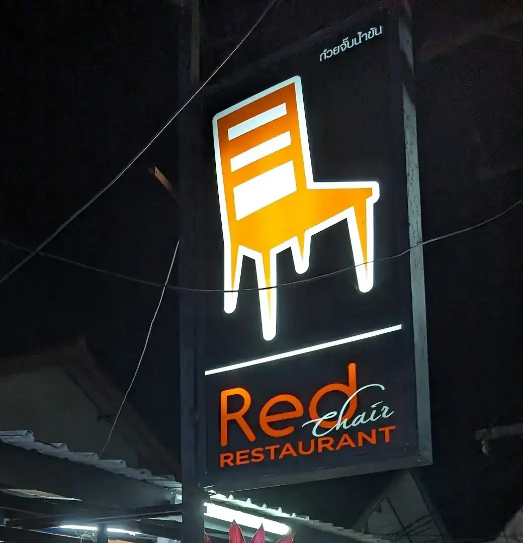 The Red Chair sign lit up at night: an orange chair above the restaurant's name