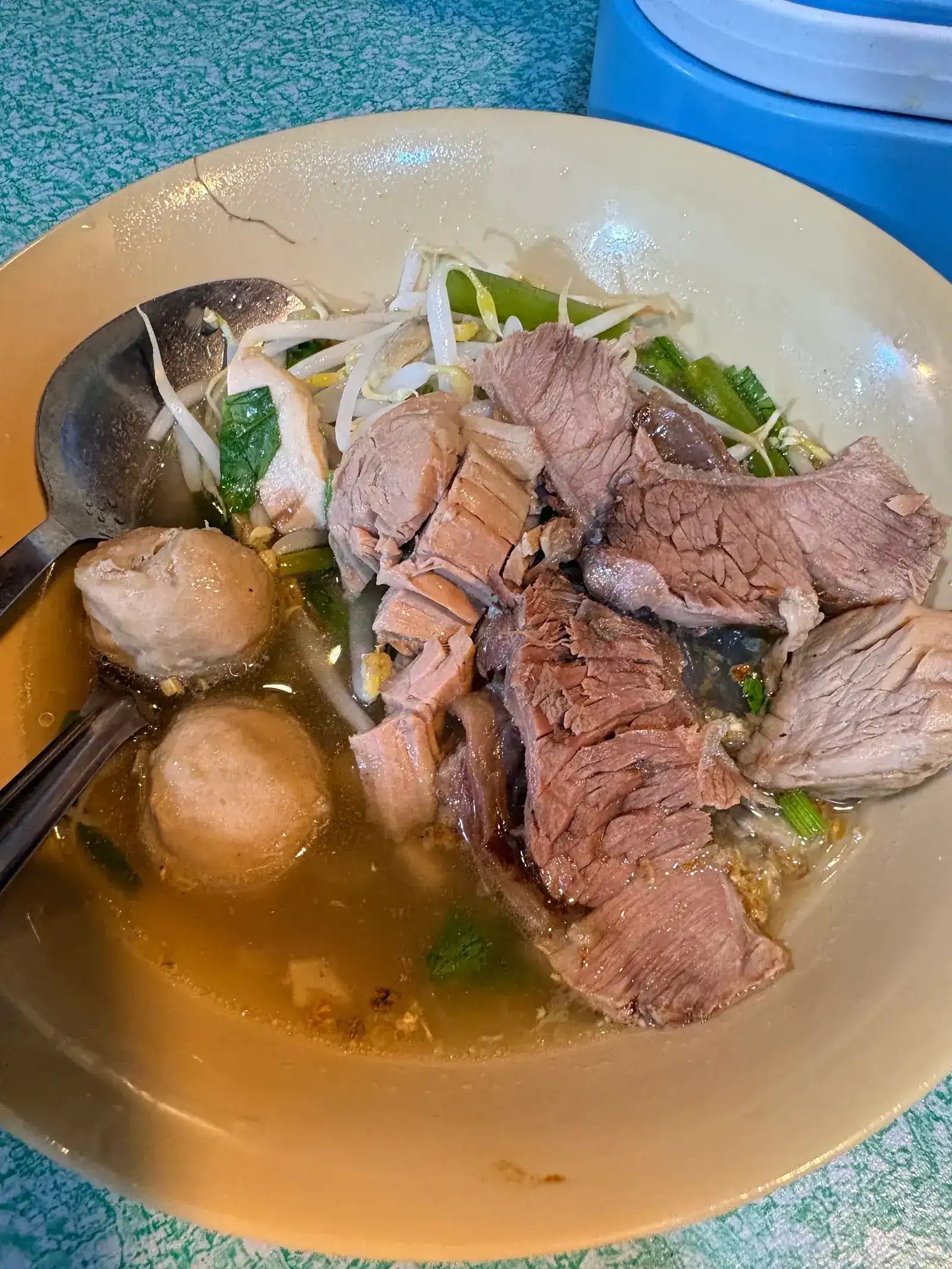A bowl of beef noodle soup with sliced beef, meatballs and bean sprouts