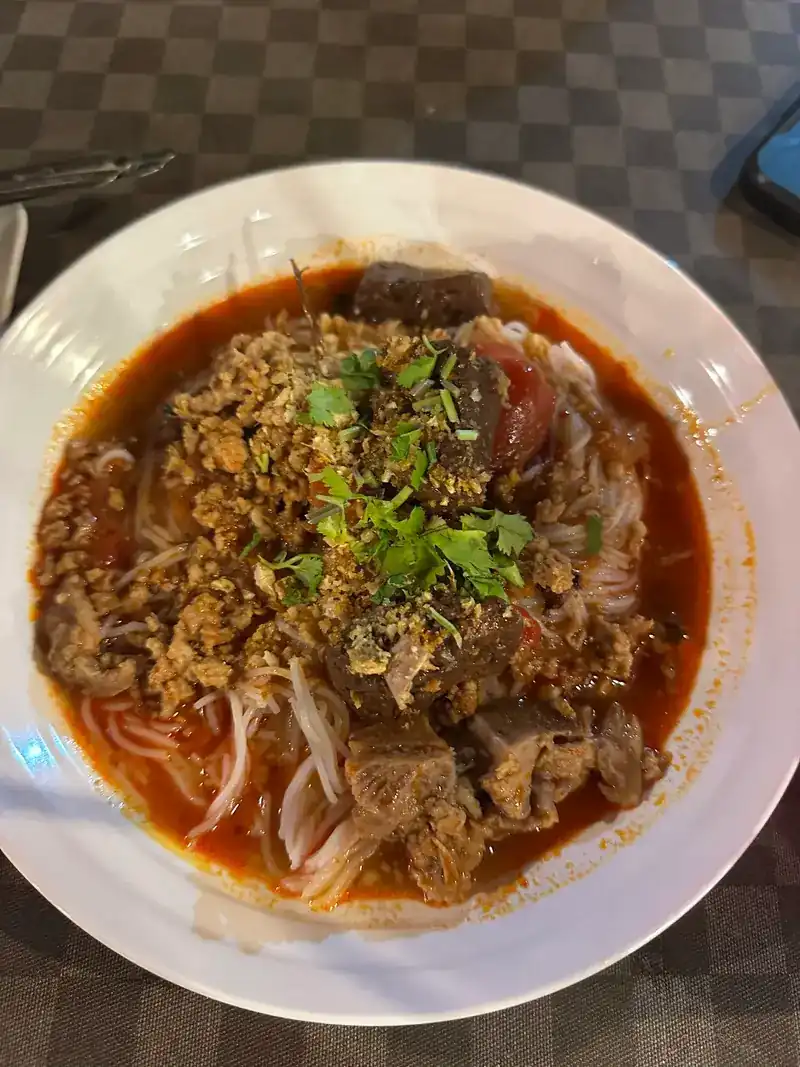 Noodles in a red broth topped with herbs