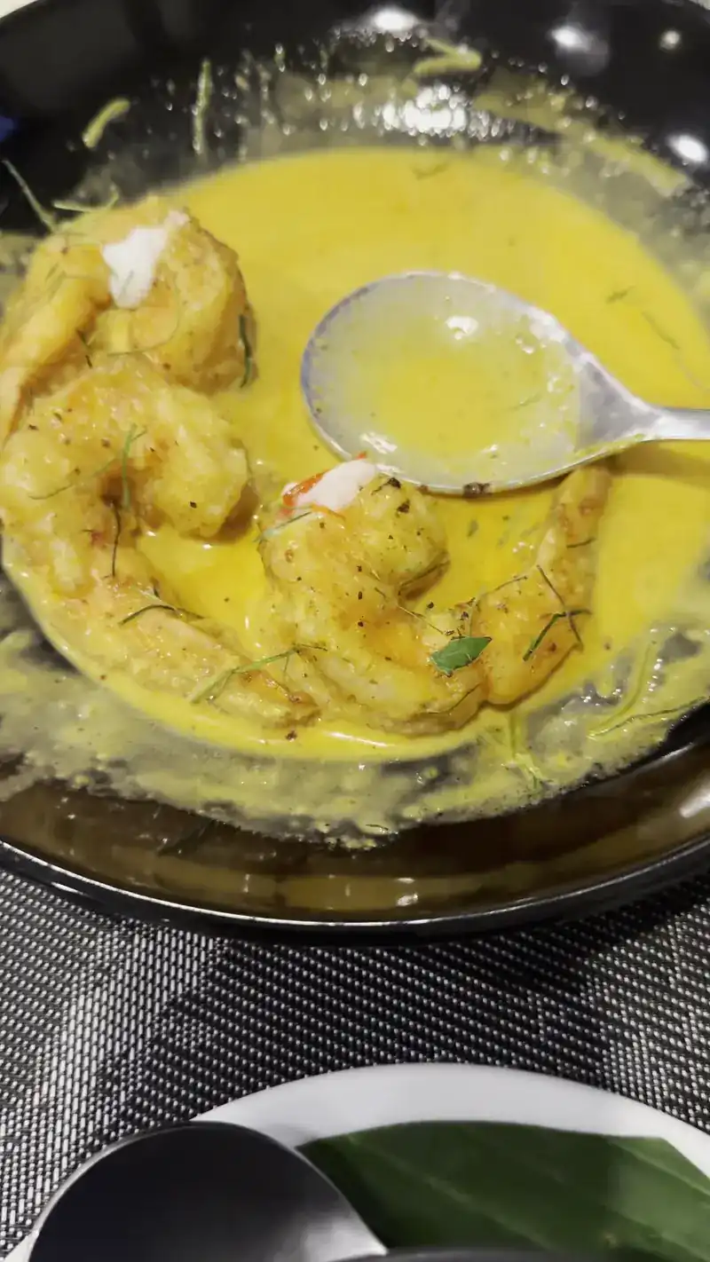 Prawns in a yellow coconut sauce in a dark bowl