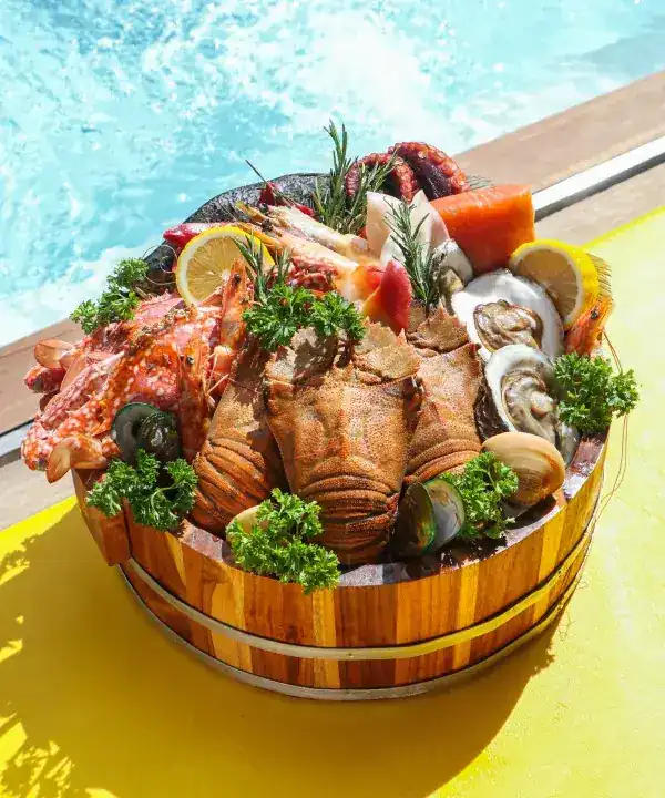 Wooden tub of lobster, prawns, crab, oysters and clams beside the pool
