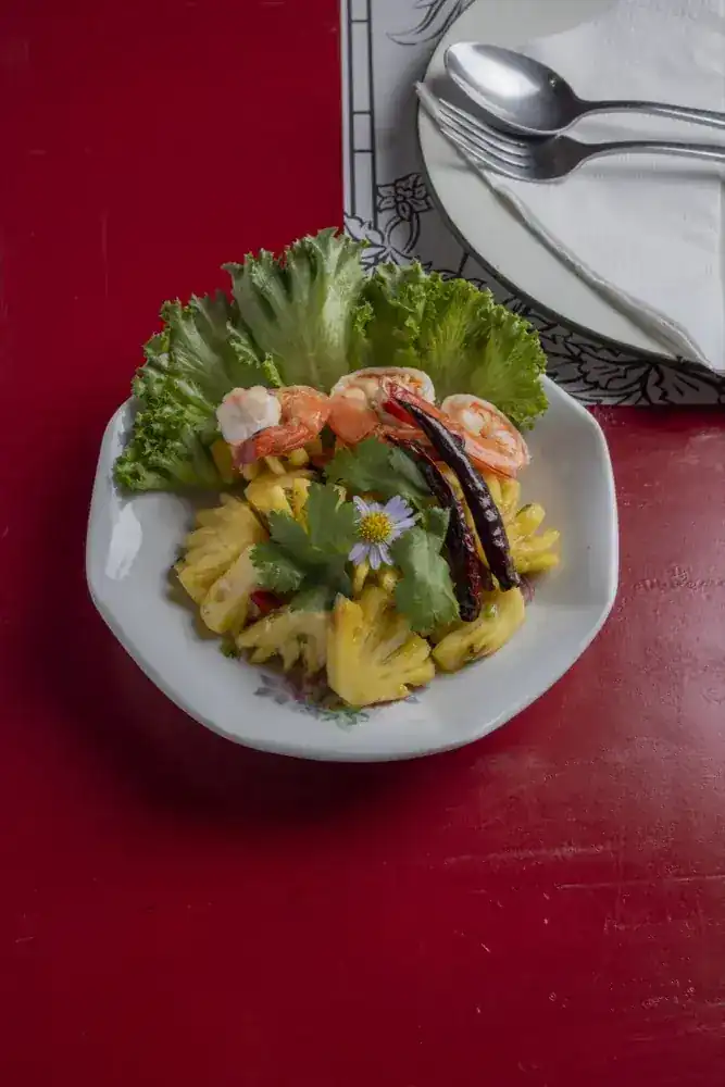 Phuket pineapple salad with prawns, dried chilli and lettuce on the red table