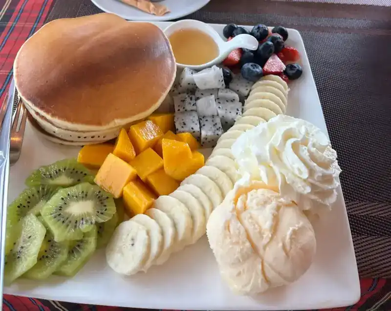 Pancakes with mango, kiwi, banana, dragon fruit, berries, whipped cream and ice cream