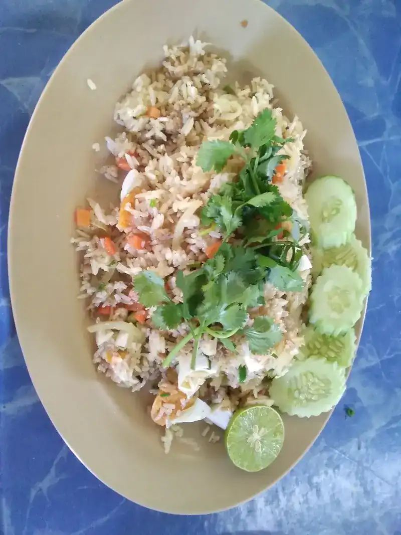 Fried rice with coriander, sliced cucumber and a wedge of lime on an oval plate