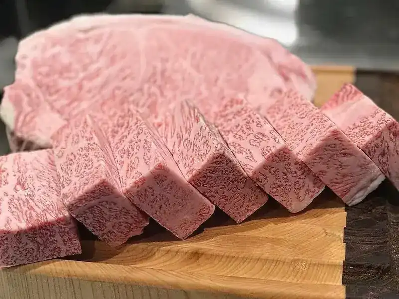 A block of marbled wagyu cut into thick slices on a wooden board