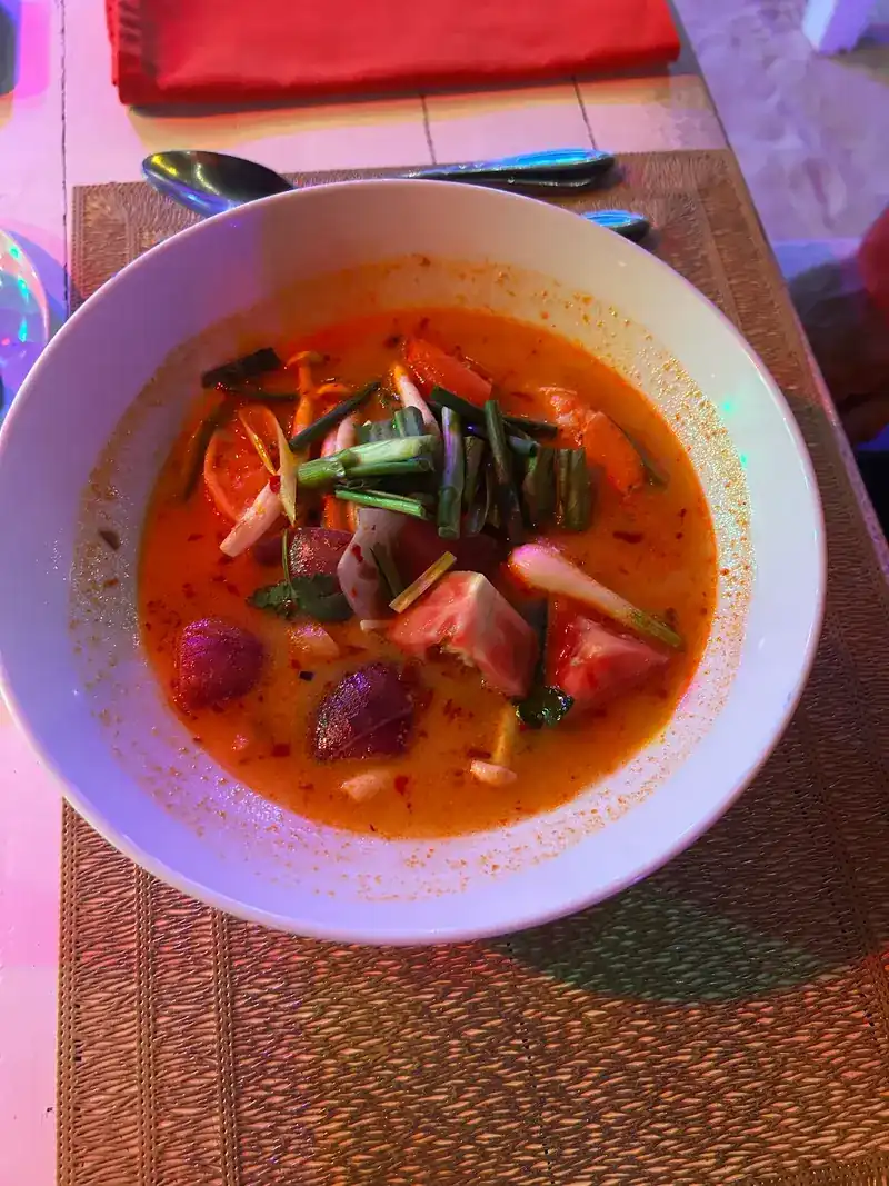 A bowl of spicy Thai soup on a woven place mat