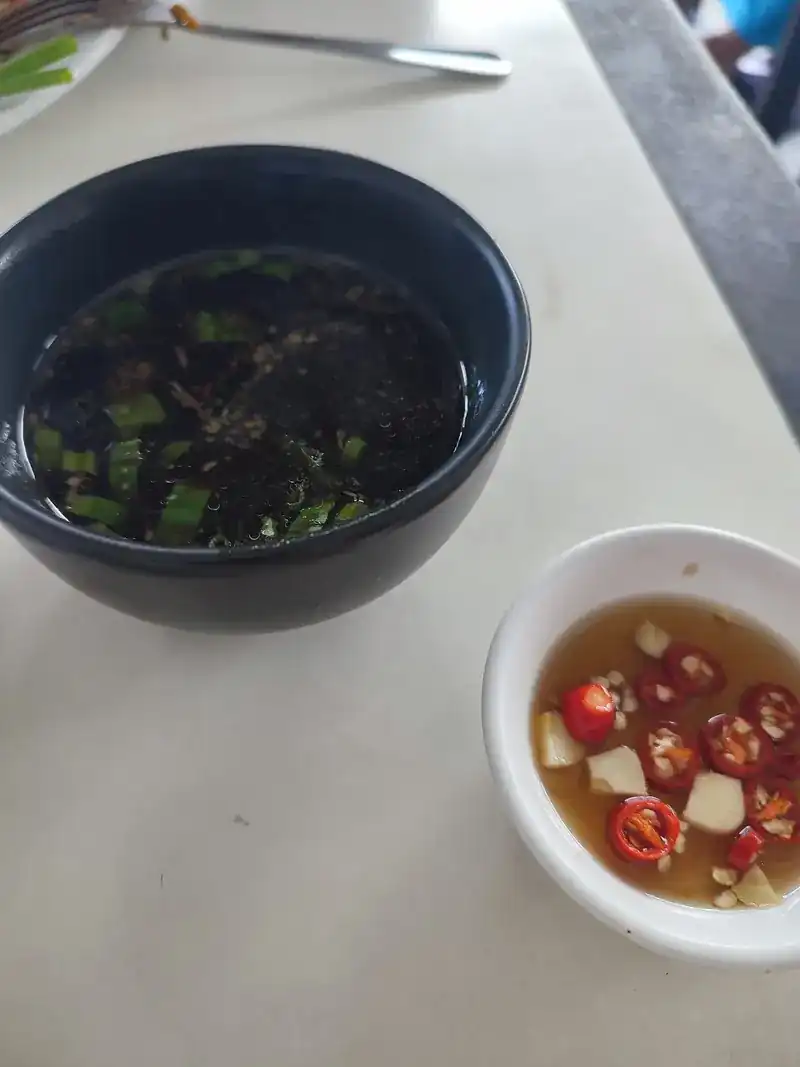 A bowl of soup and a dish of chillies in fish sauce