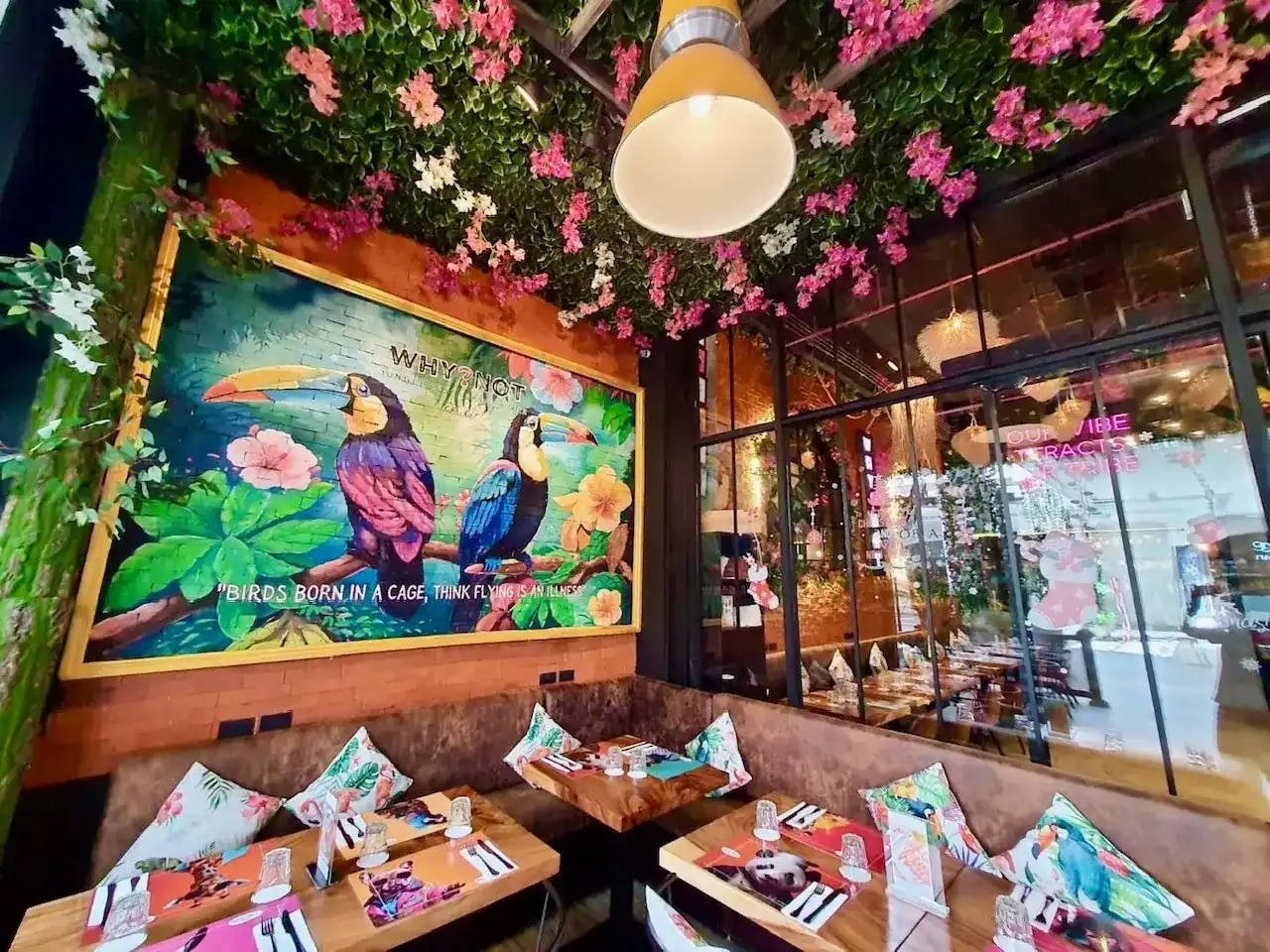 Toucan mural and a ceiling of pink bougainvillea over the banquette tables / ภาพวาดนกทูแคนบนผนังและเพดานดอกเฟื่องฟ้าสีชมพูเหนือโต๊ะนั่ง